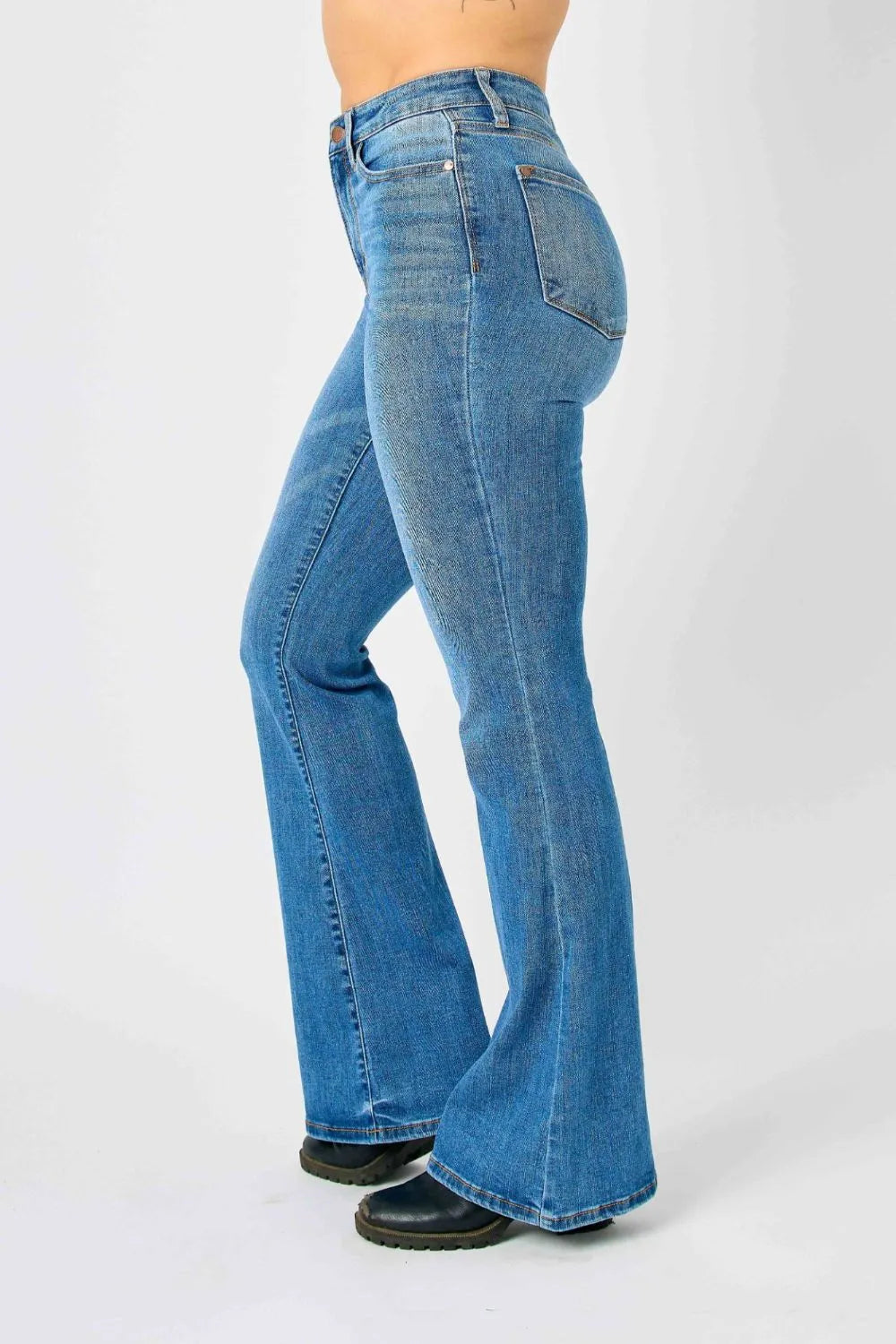 Model posing with her hand on the pocket, showing the side fit of Judy Blue high-waisted flare jeans.