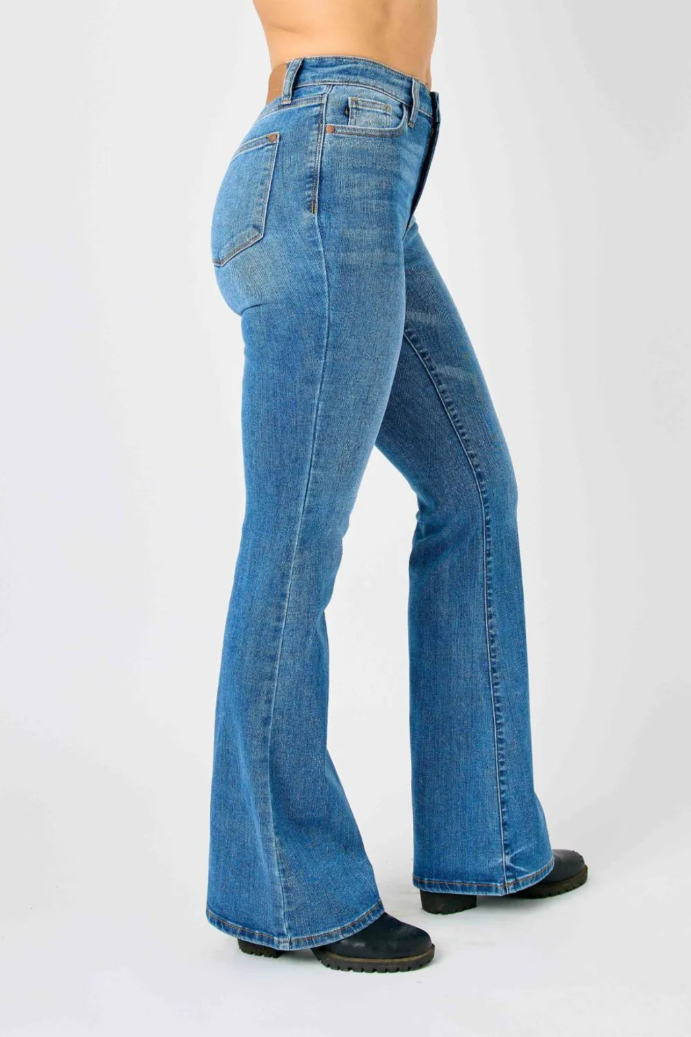 Plus-size model standing confidently in Judy Blue high-waisted flare jeans, emphasizing the flattering fit.