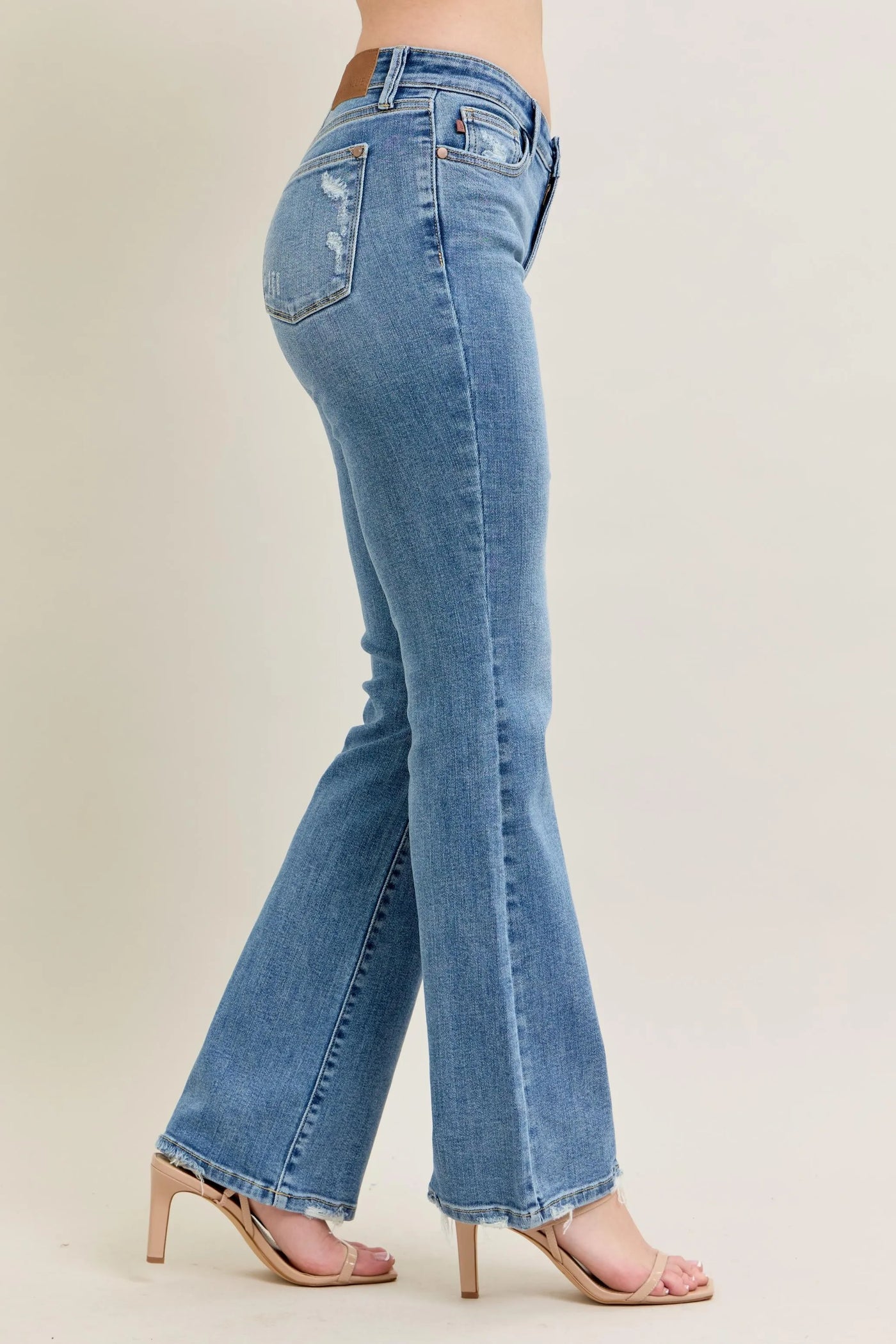 Angled front view of Judy Blue Full Size Mid Rise Wash Destroy Hem Bootcut Jeans Plus Size, showcasing the silhouette.