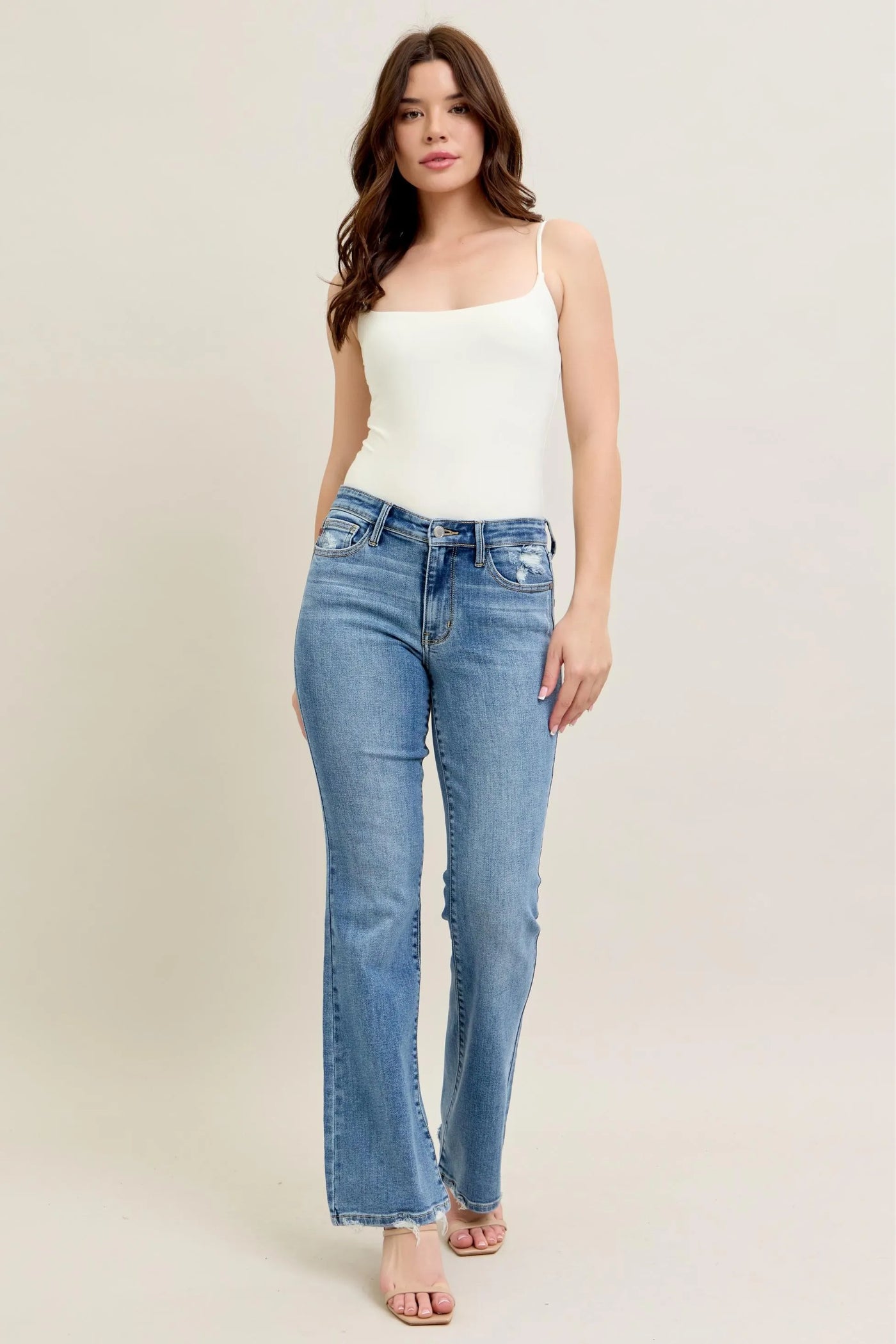 Model wearing Judy Blue Full Size Mid Rise Wash Destroy Hem Bootcut Jeans Plus Size from the front.