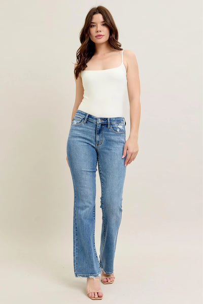 Model wearing Judy Blue Full Size Mid Rise Wash Destroy Hem Bootcut Jeans Plus Size from the front.