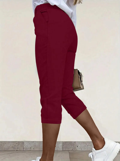 Back view highlighting the design of pleated detail pants in burgundy