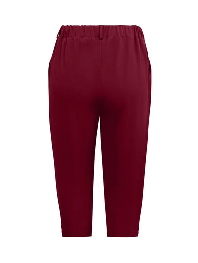 Model wearing pleated detail pants in burgundy