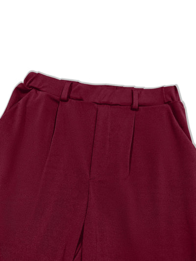 Detail view of waistband and pleat on burgundy pleated pants