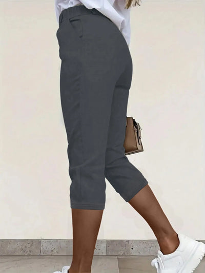 Back view highlighting the design of pleated detail pants in dark gray"