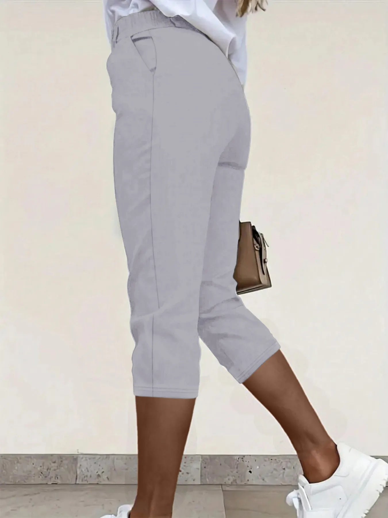 Back view highlighting the design of pleated detail pants in gray