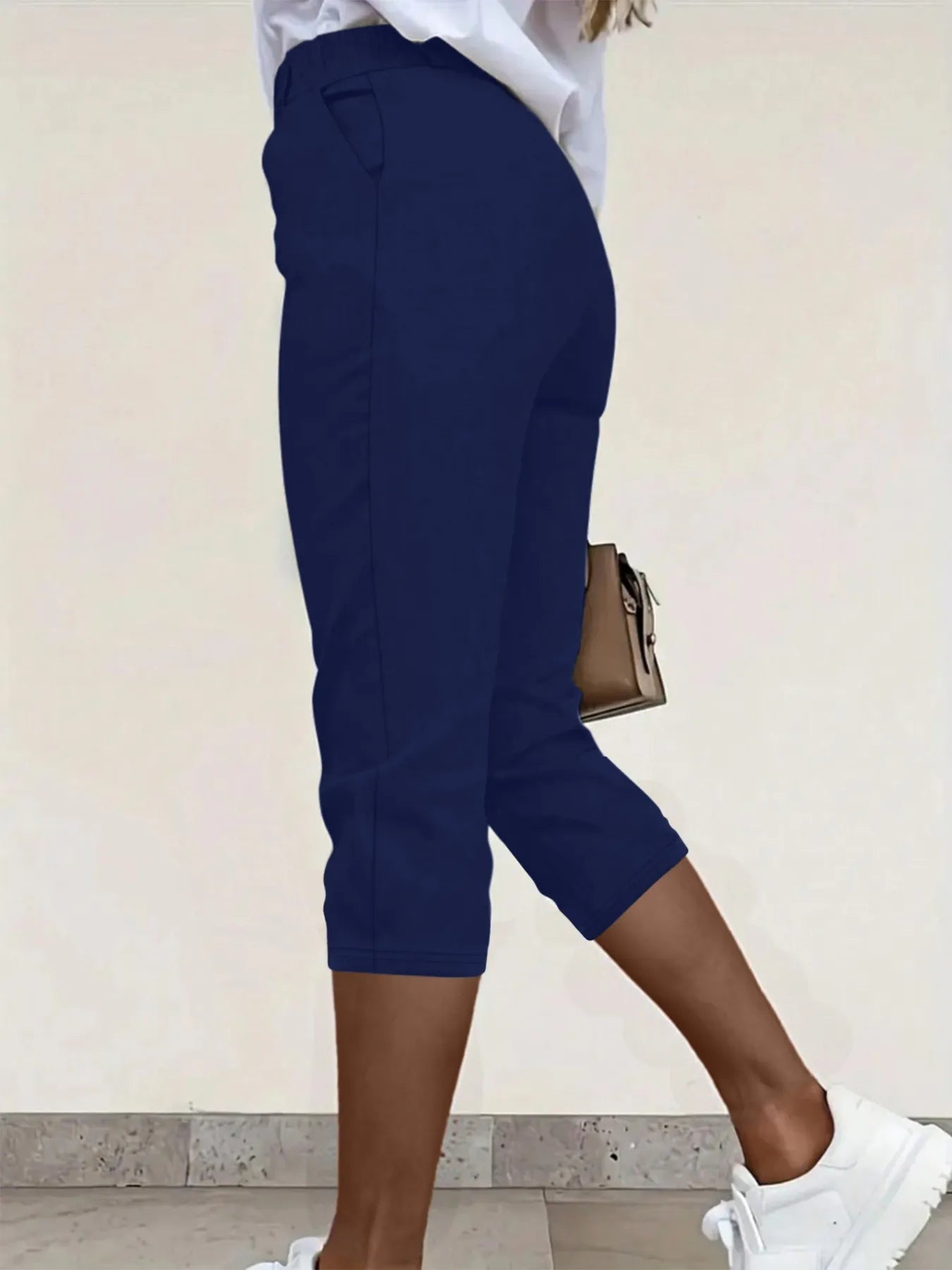 Back view highlighting the design of pleated detail pants in navy