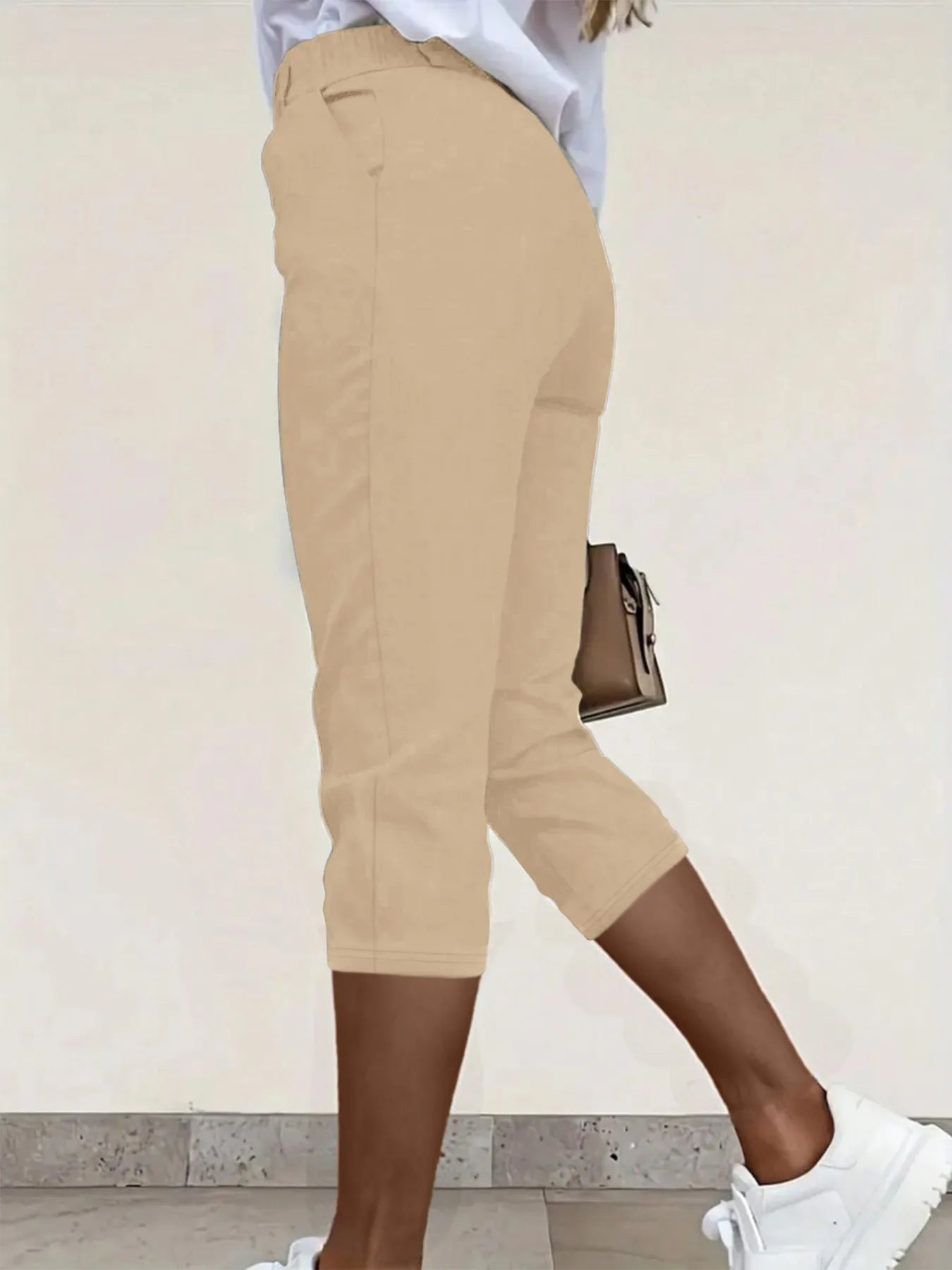 Back view highlighting the design of pleated detail pants in tan