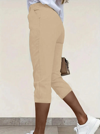 Back view highlighting the design of pleated detail pants in tan
