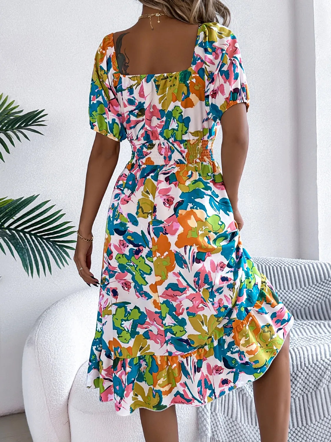 Back view of model wearing Ruffled Hem Smocked Floral Short Sleeve Midi Dress, showcasing the ruffled hem and smocked bodice.