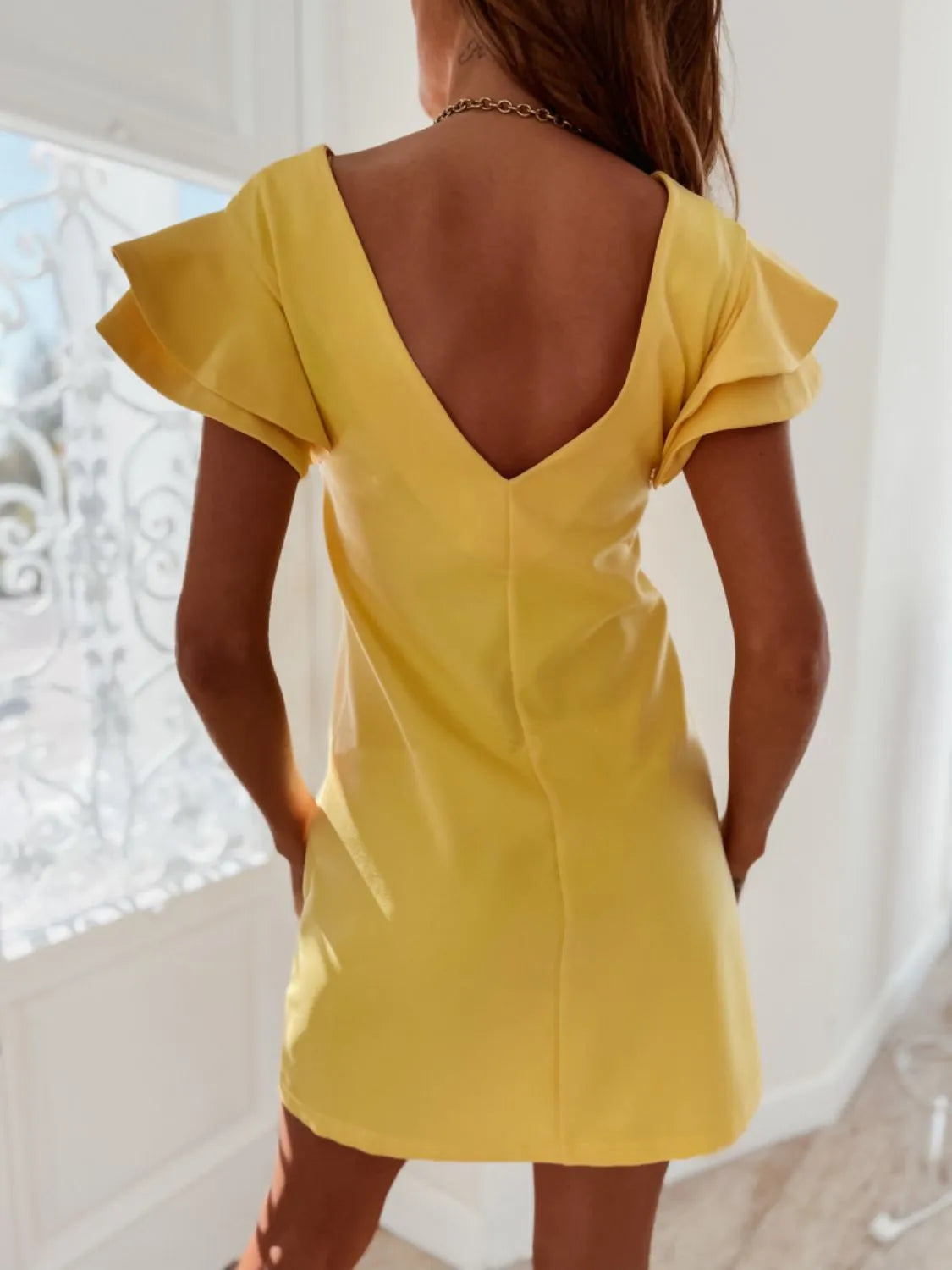 Back view highlighting the design of Ruffled Layered Short Sleeve Mini Dress in Yellow